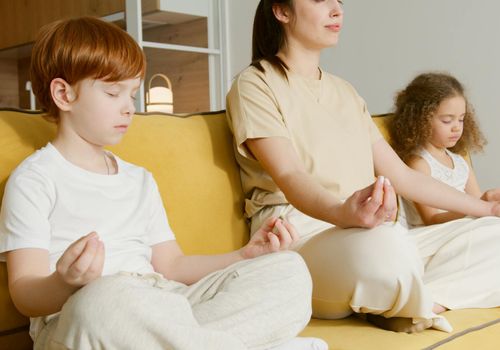 Child sitting calmly, practicing breathing exercises with closed eyes.