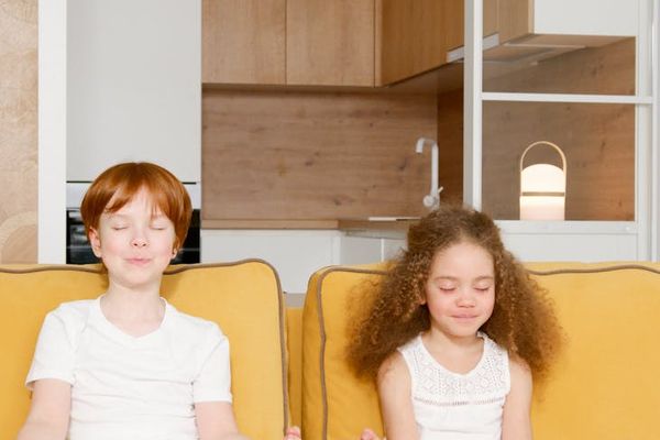 Two children sitting quietly and meditating with eyes closed.