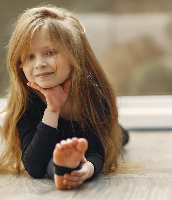 Young girl playfully practicing a yoga pose in a bright, calm room, smiling.